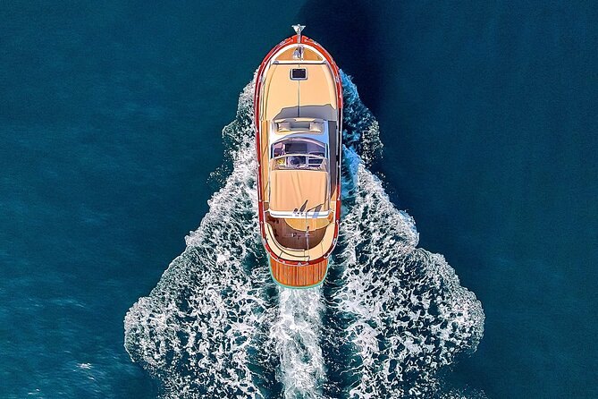 A traditional wooden gozzo under way seen from directly above, its wake spreading behind