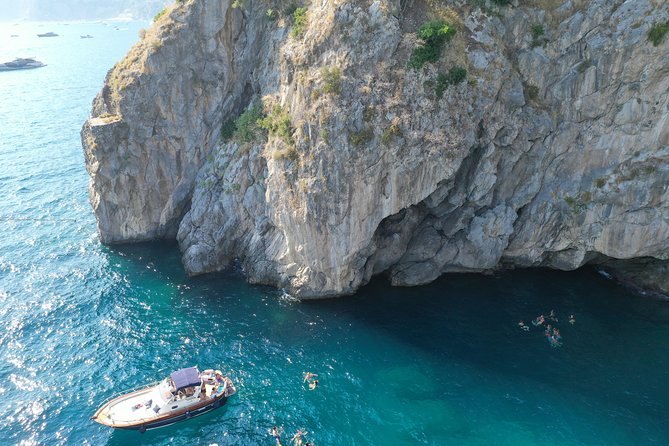 A small boat under a sheer limestone cliff on the Amalfi Coast